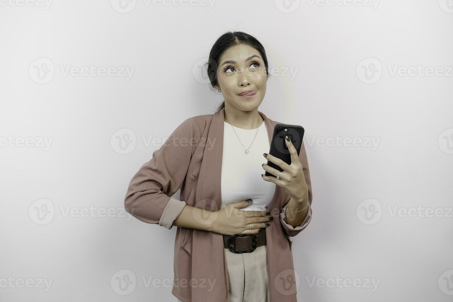 un hambriento asiático mujer empleado es participación su teléfono y imaginando sabroso comida ella quiere a orden, aislado en blanco color antecedentes. foto