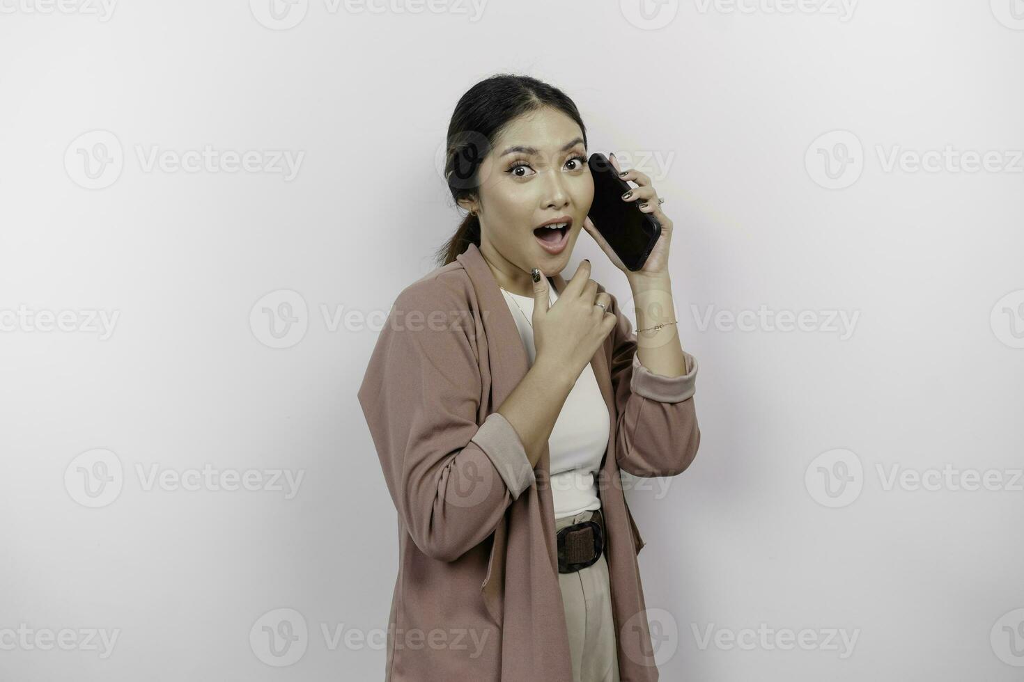 Shocked young Asian woman employee wearing cardigan is having a phone call, isolated by white background photo