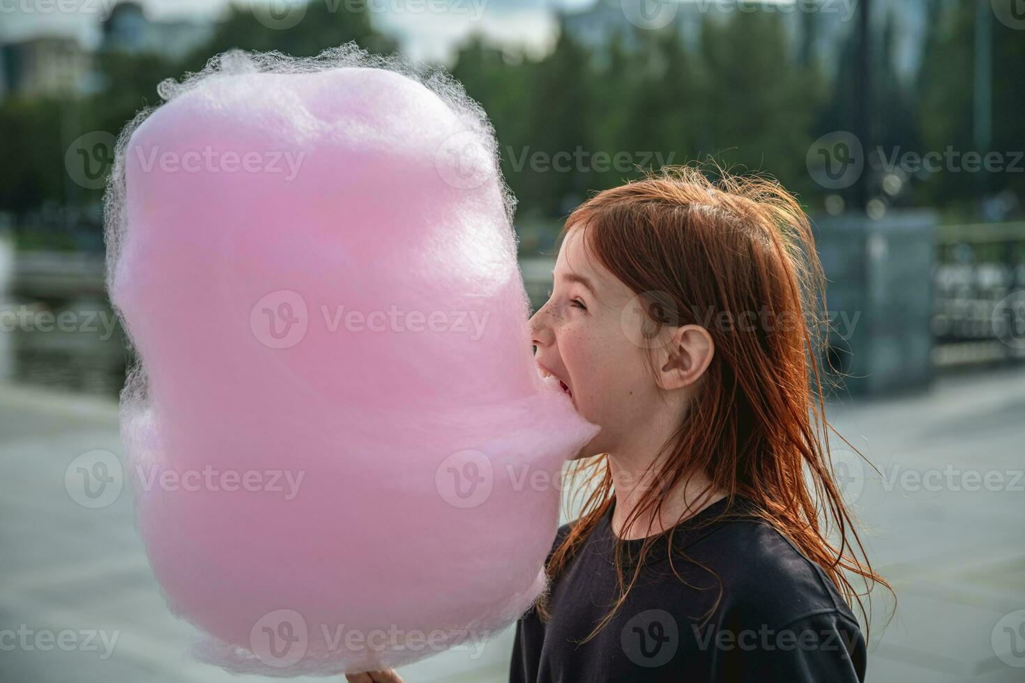 linda niña comiendo grande rosado algodón caramelo foto