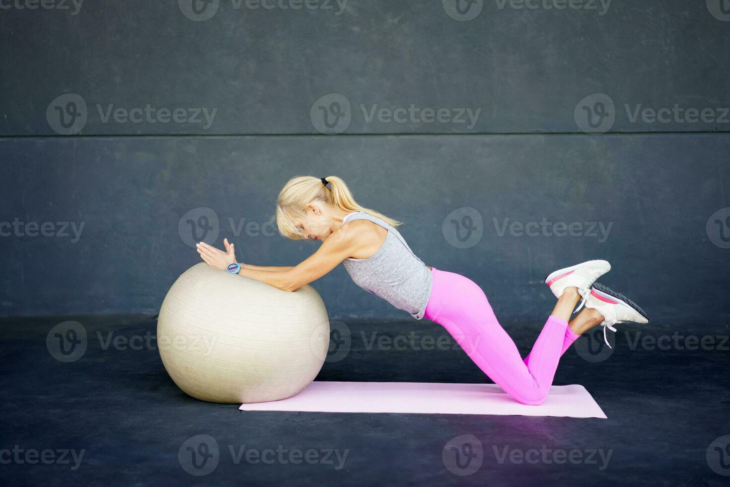 Adult woman doing exercise with fit ball in daylight photo