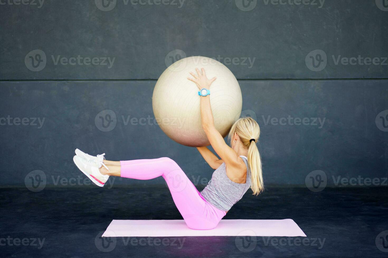 Fit woman doing exercise with fitness ball at club photo