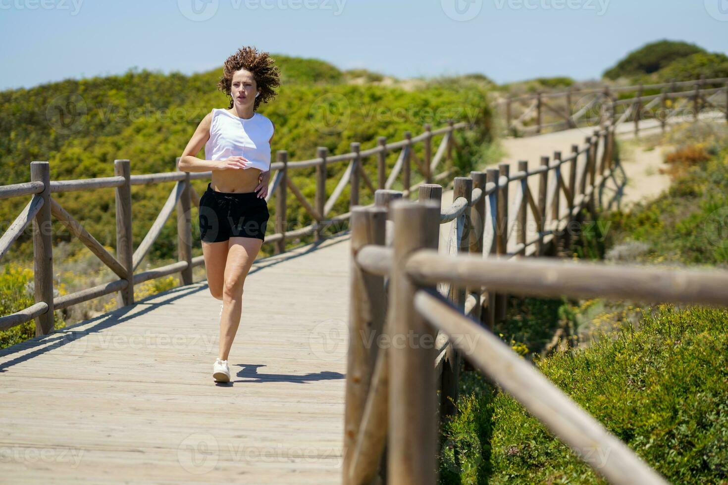 Determined woman running on wooden path in countryside photo