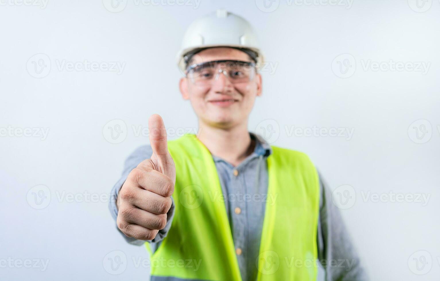 Smiling young engineer gesturing approval with thumb. Cheerful engineer giving thumbs up to the camera isolated photo