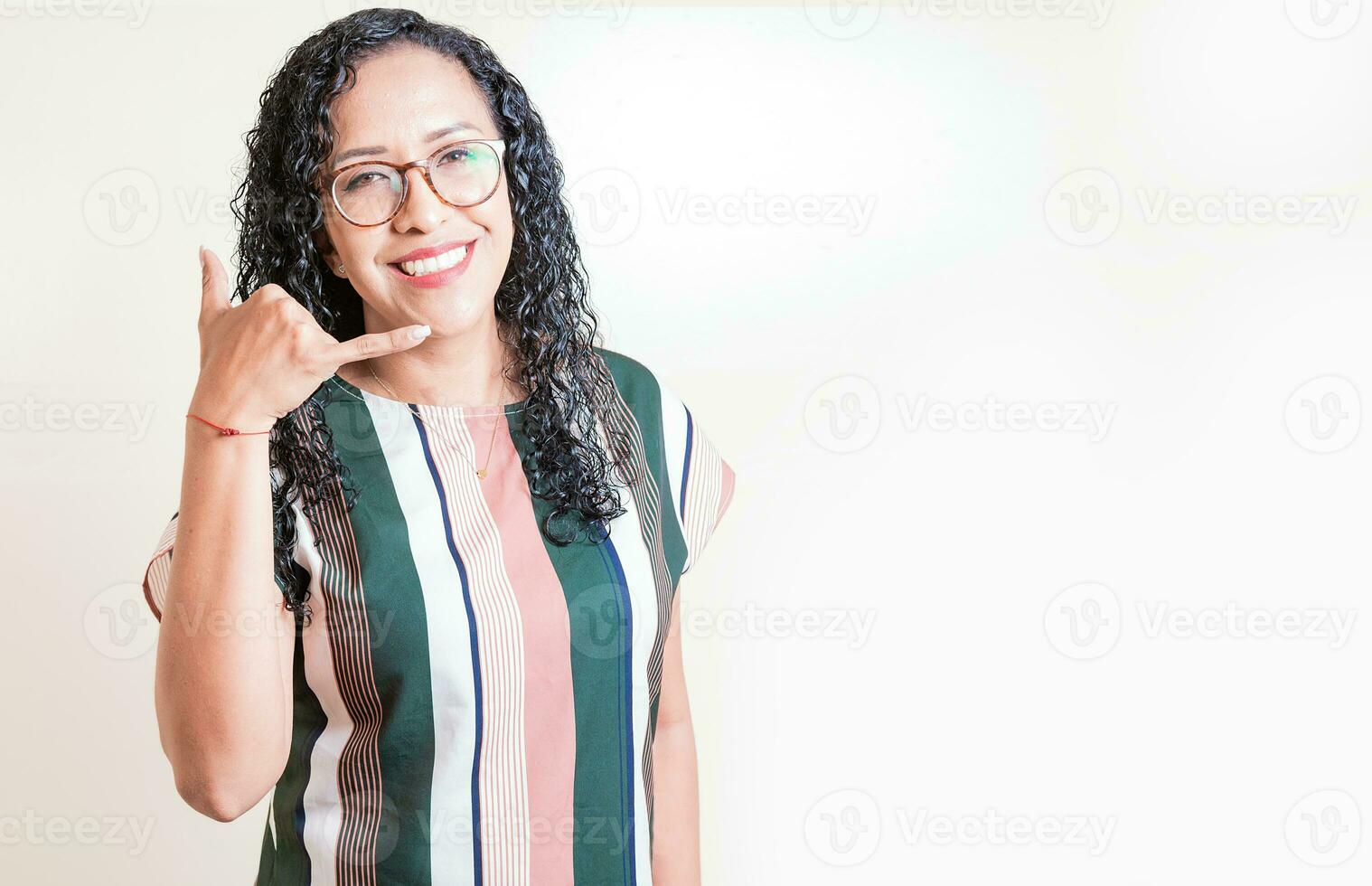 Happy girl in glasses gesturing call me with hand isolated. Latin woman in glasses gesturing call with fingers isolated. photo