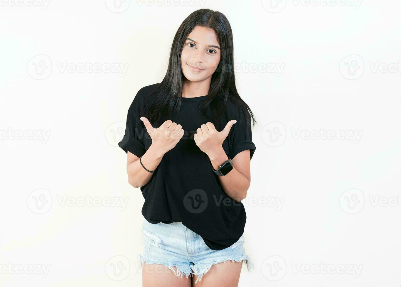 Smiling latin girl pointing both sides on isolated background. Cheerful girl recommending with fingers, isolated. Cute young girl pointing an offer with both fingers photo