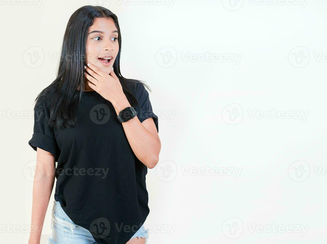 Shocked young girl looking at a promotion to the side. Amazed people with hand on chin looking at blank space. Surprised teen girl looking at an advertisement to side photo
