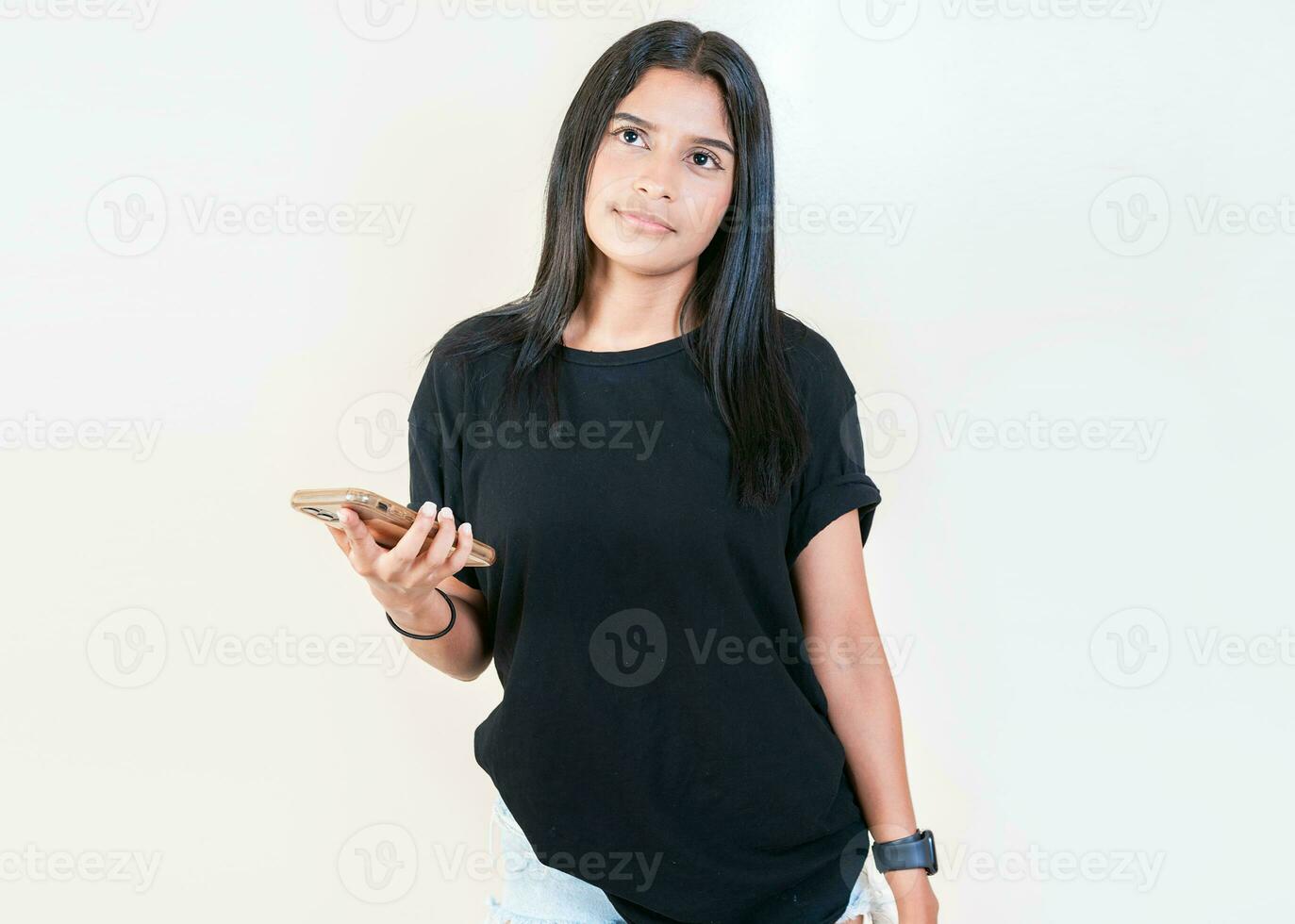 Pensive latin girl holding smart phone on white background. Thoughtful attractive girl holding phone isolated photo