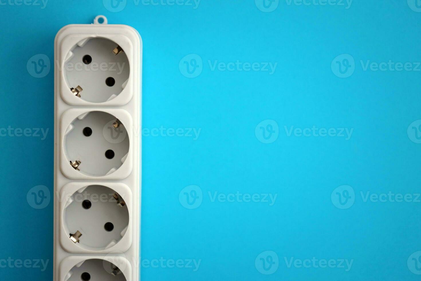 White electrical multi plug extender with european socket on bright blue background photo
