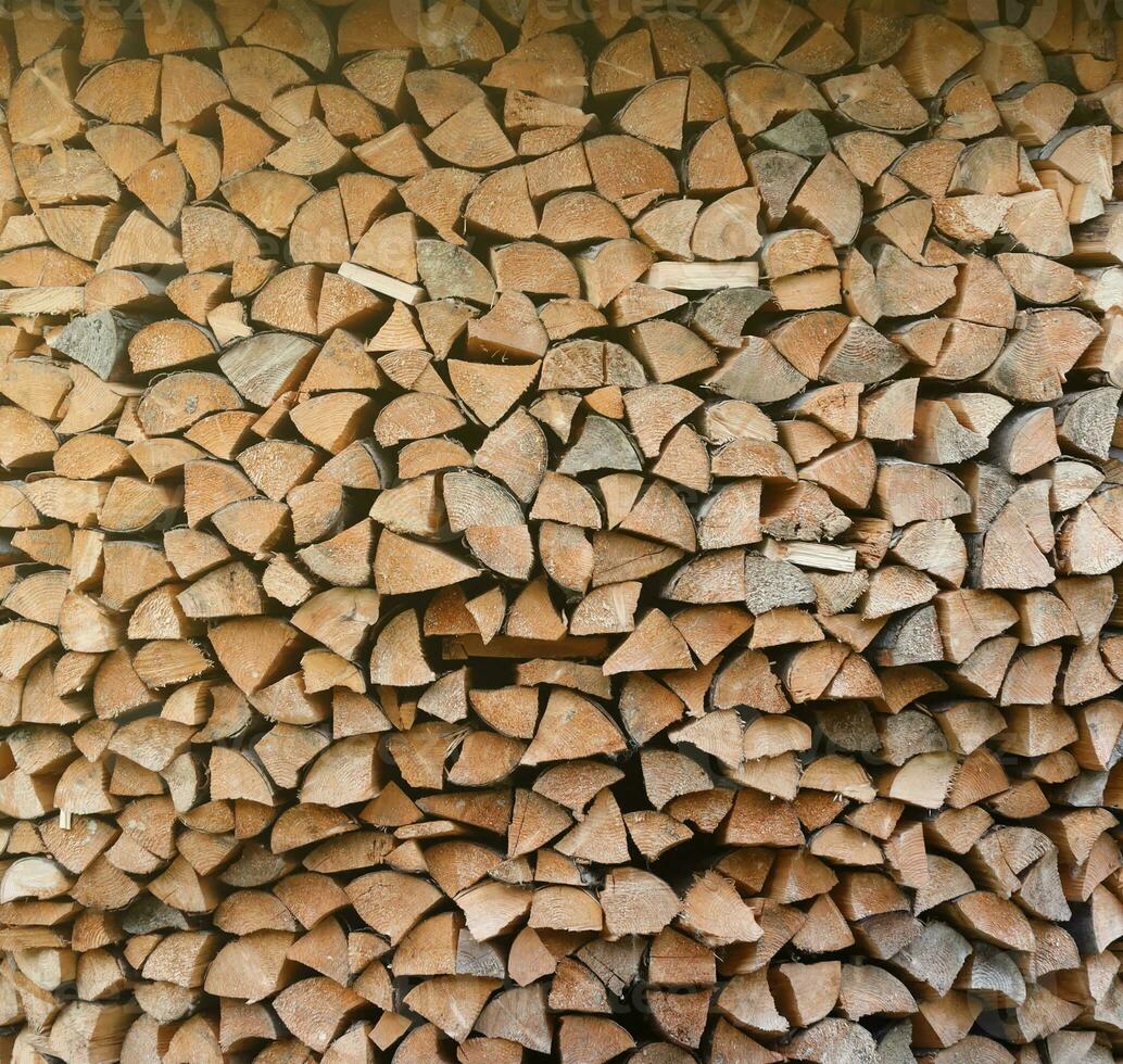 Firewood stacked near the wooden wall of old hut. Many chopped logs of firewood photo
