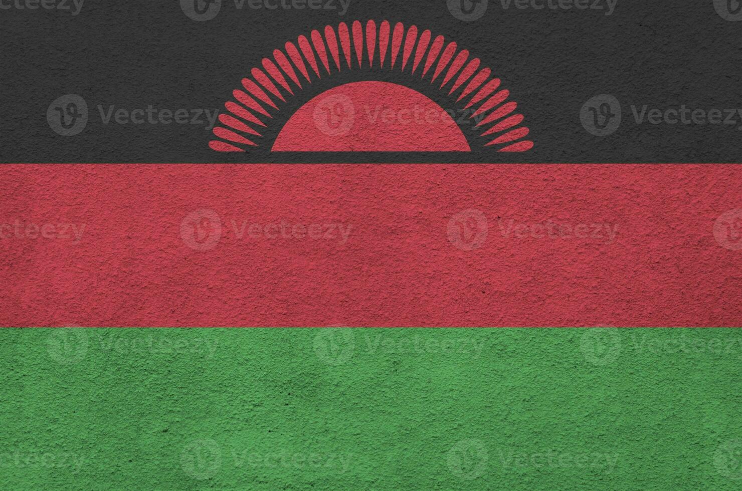 Malawi flag depicted in bright paint colors on old relief plastering wall. Textured banner on rough background photo
