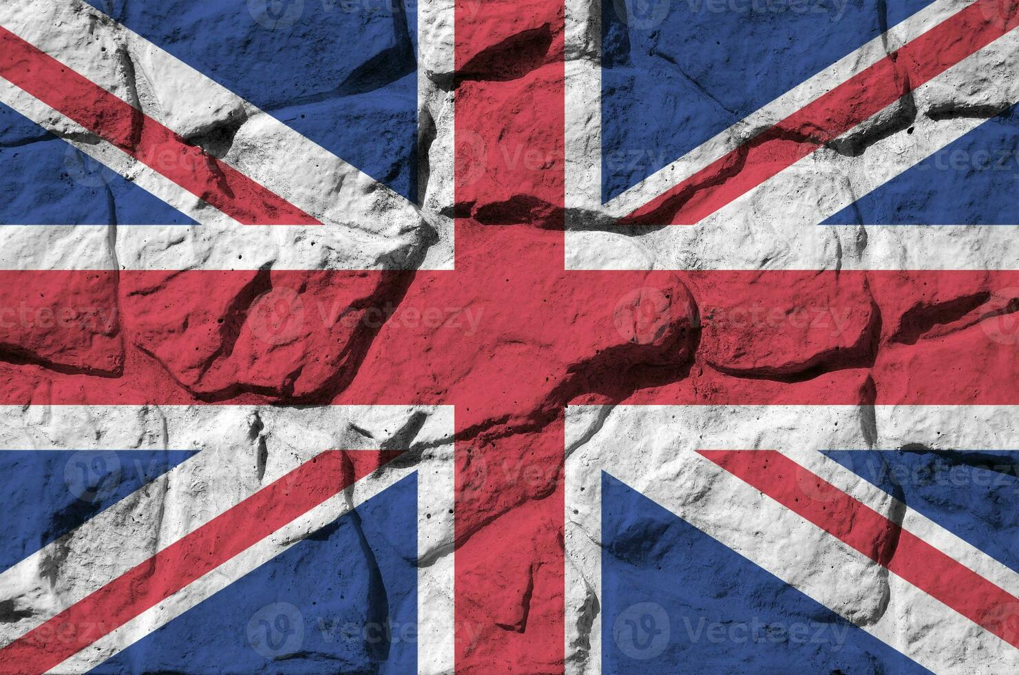 Great britain flag depicted in paint colors on old stone wall closeup. Textured banner on rock wall background photo