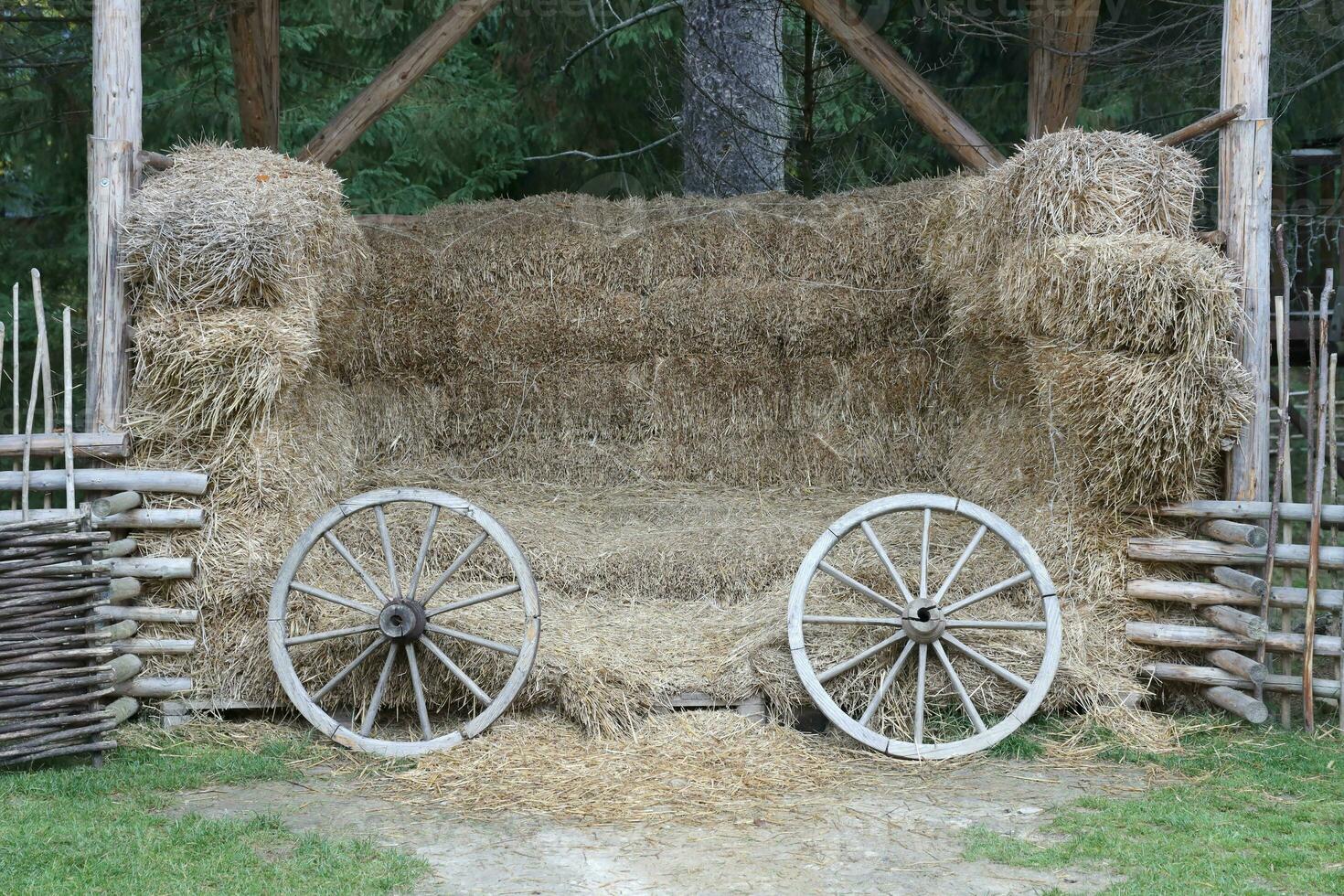 Place with stacks of hay cubes and rustic wooden wheels of old cart photo