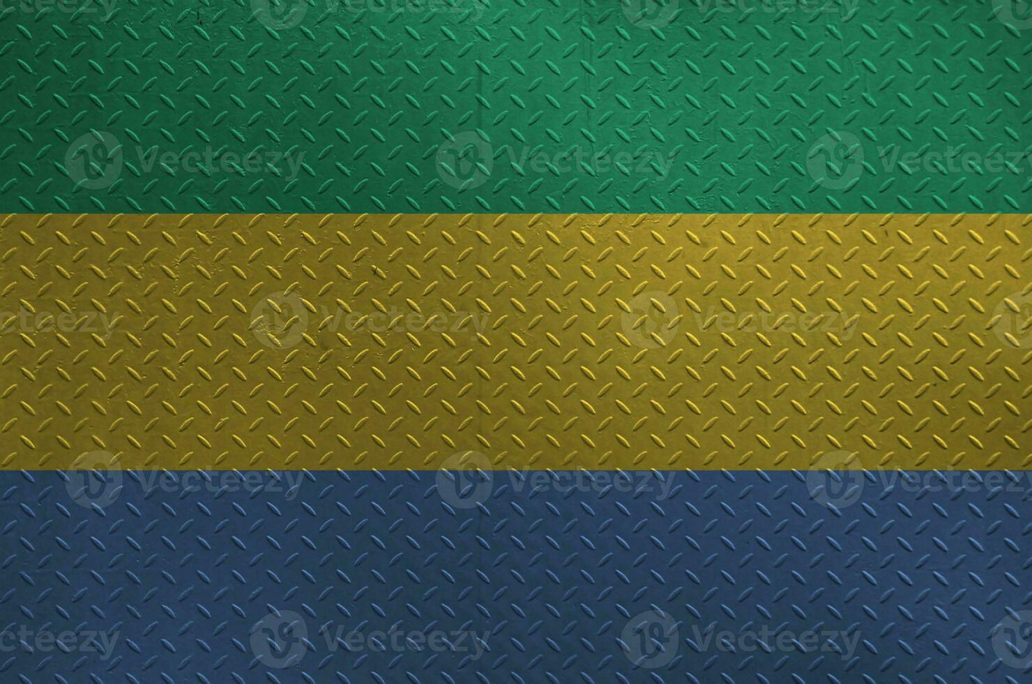 Gabon flag depicted in paint colors on old brushed metal plate or wall closeup. Textured banner on rough background photo