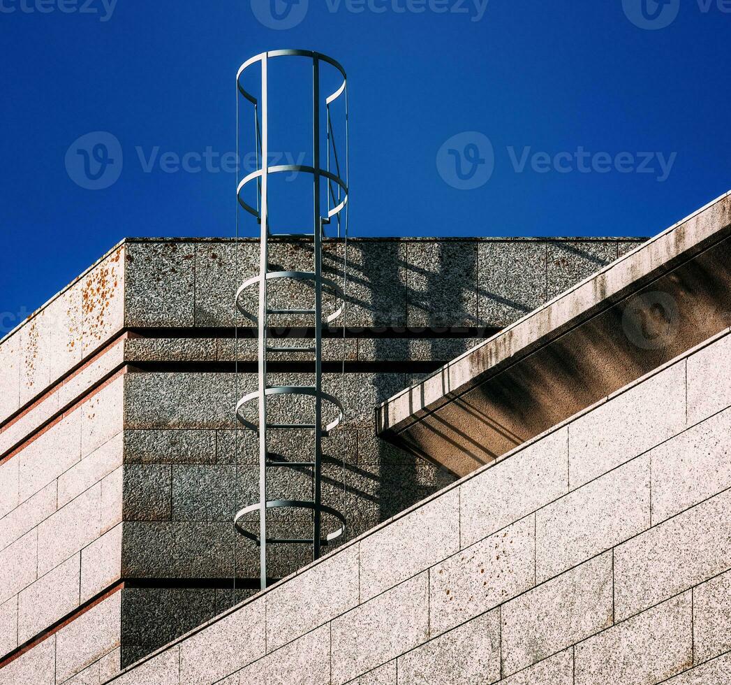 Low perspective view of an outdoor fire escape ladder on commercial building wall photo
