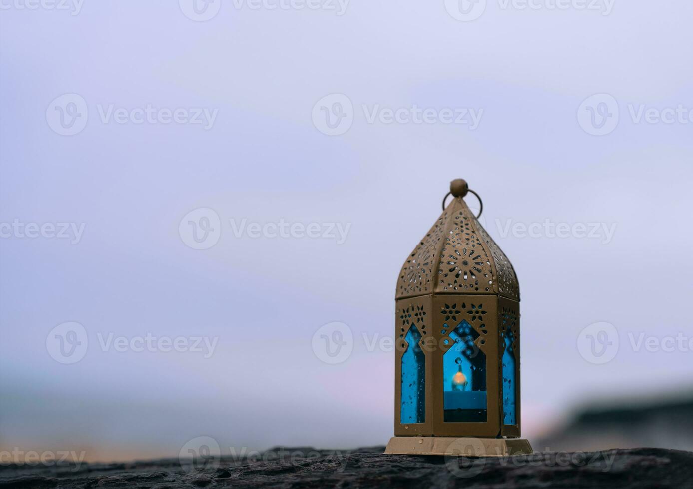 Islamic Lantern on rock with blurry sea beach background.Eid decorative traditional lamps illuminated ready for the Holy season of Ramadan Kareem,Eid Al fitr,Eid al Adha,Eid Mubarak,Muharram photo