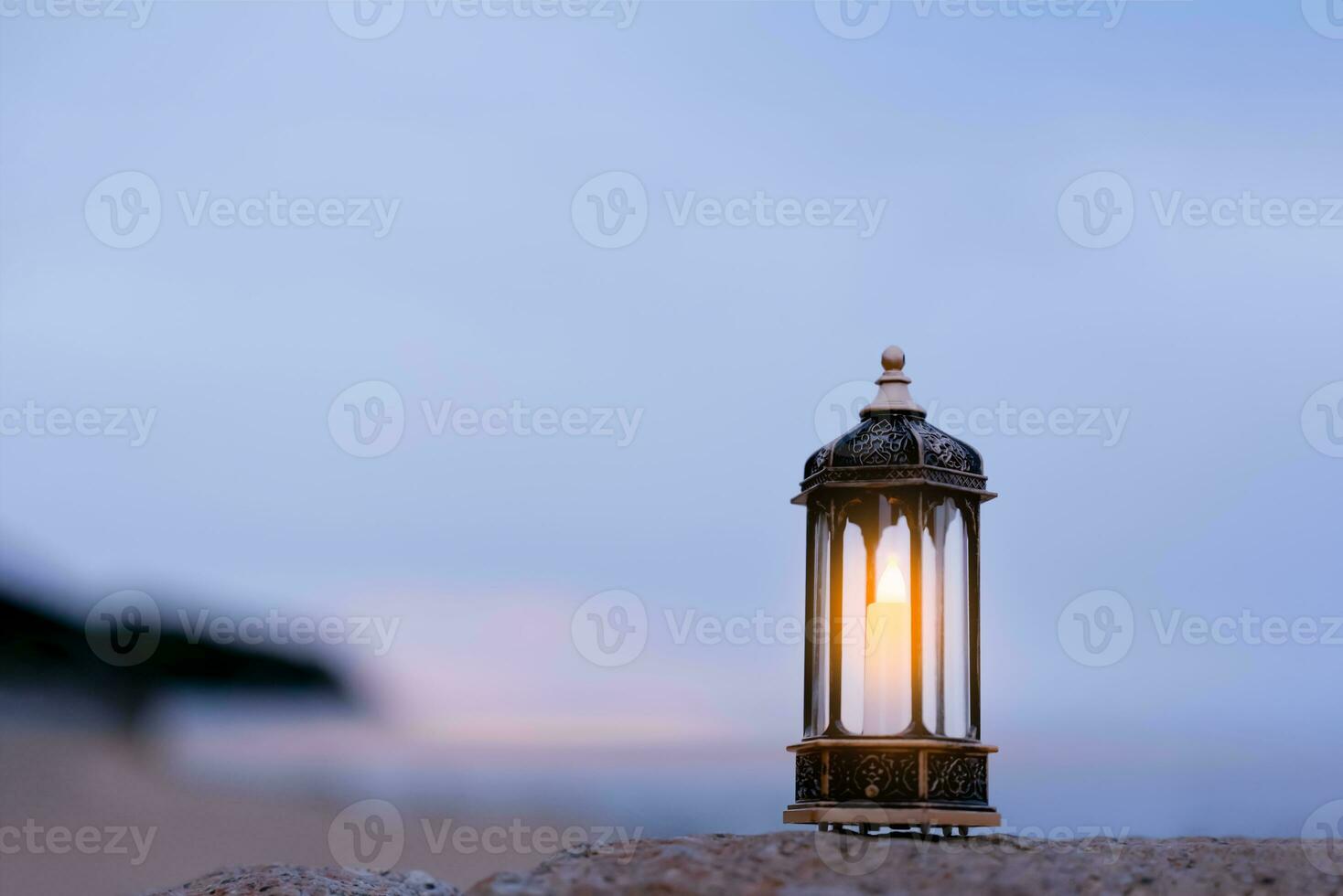 Islamic Lantern on rock with blurry sea beach background.Eid decorative traditional lamps illuminated ready for the Holy season of Ramadan Kareem,Eid Al fitr,Eid al Adha,Eid Mubarak,Muharram photo