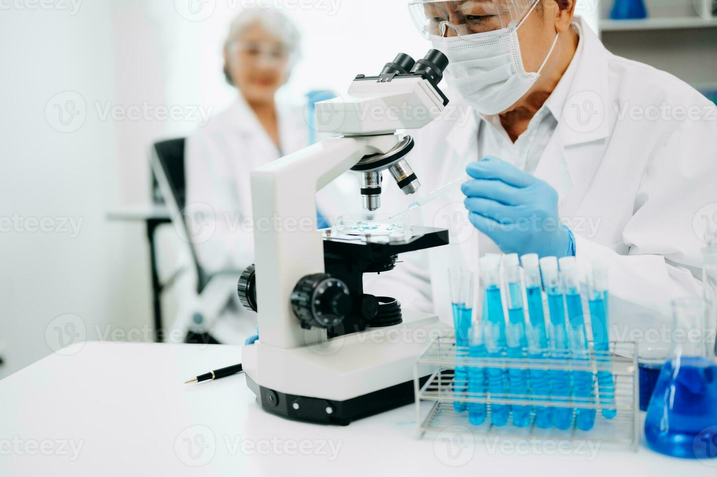 Scientists conducting research investigations in a medical laboratory, a researcher in the foreground is using a microscope in laboratory for medicine. photo