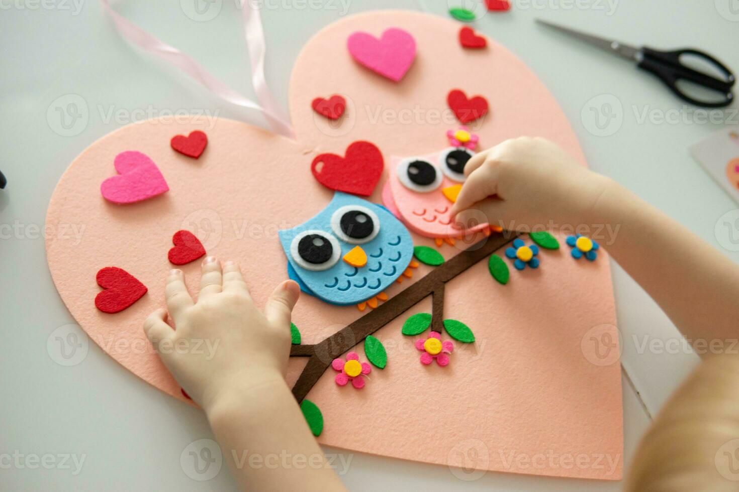 A blogger girl makes a felt craft for Valentine's Day in the shape of a heart. The concept of children's creativity and handmade. photo