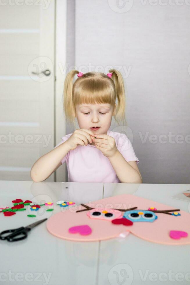 A blogger girl makes a felt craft for Valentine's Day in the shape of a heart. The concept of children's creativity and handmade. photo