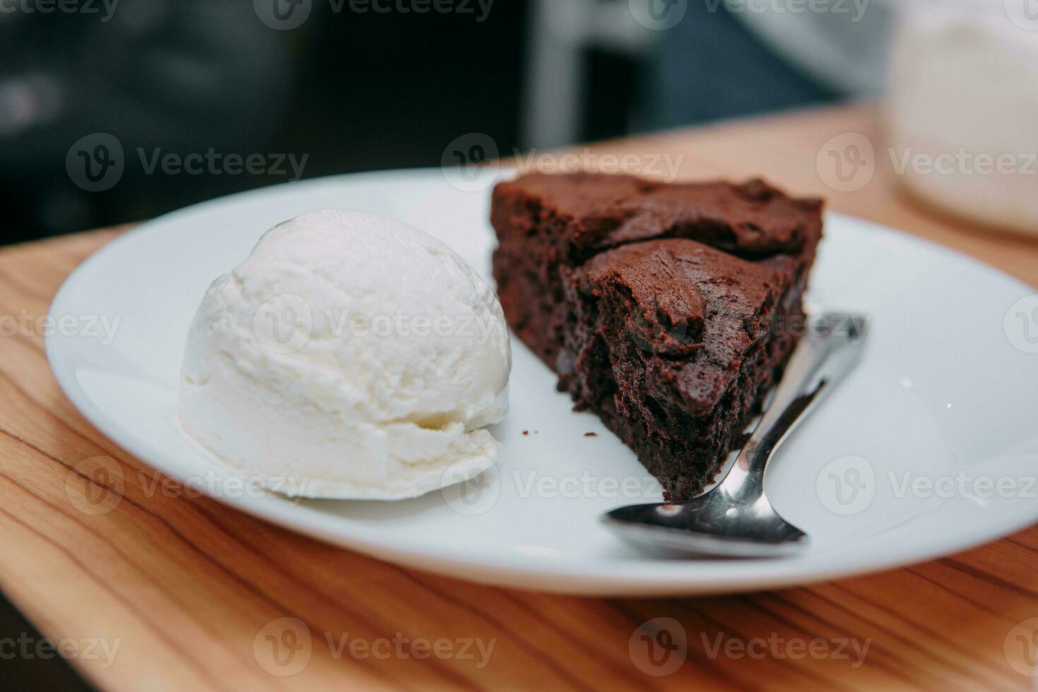 Chocolate brownie with a scoop of ice cream on a white plate. Close up. photo