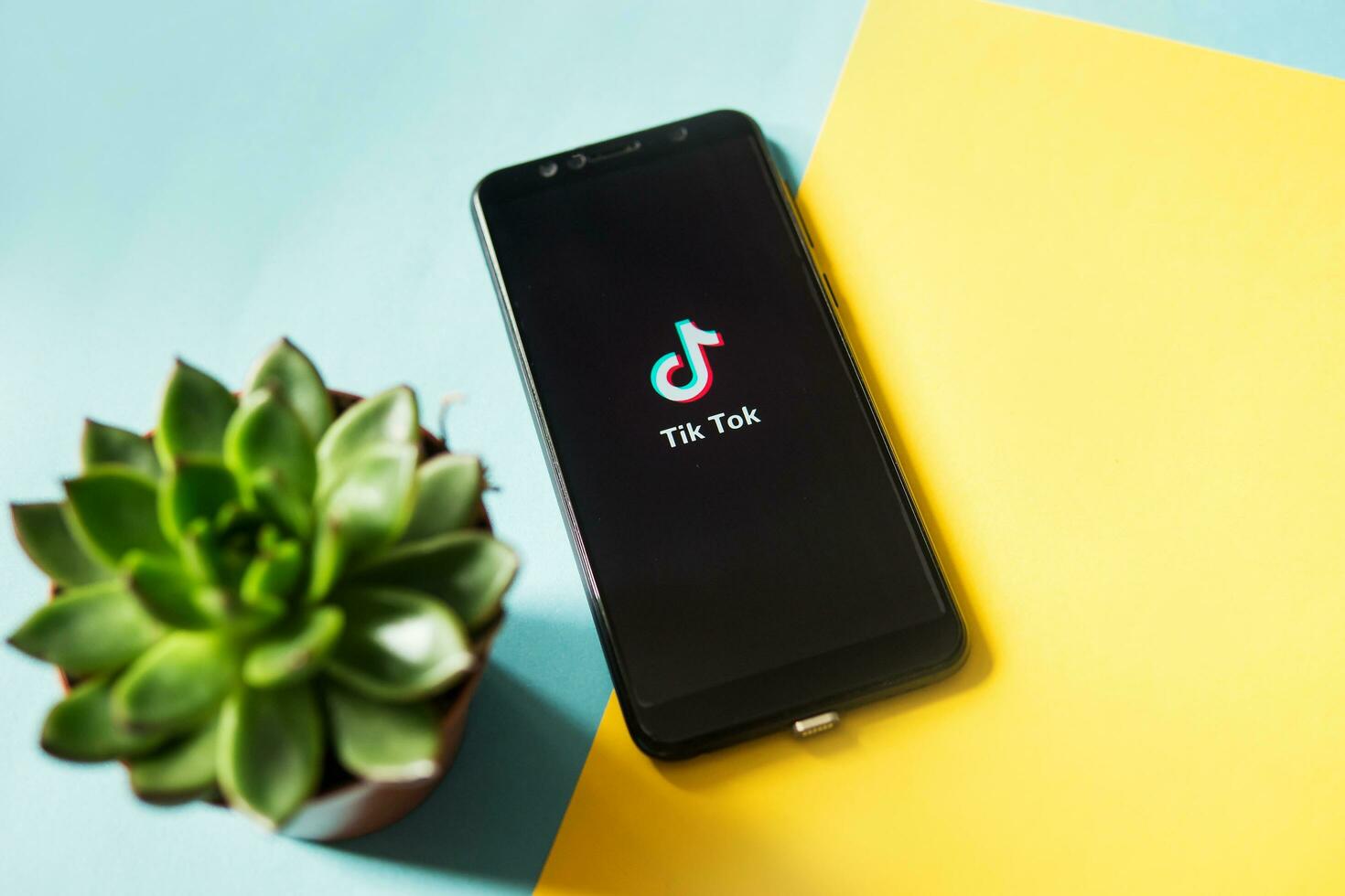 Tver, Russia - February 28, 2020 Tik tok logo on smartphone screen on blue and yellow background. Tik Tok icon. tik tok application. Tiktok Social media network. photo