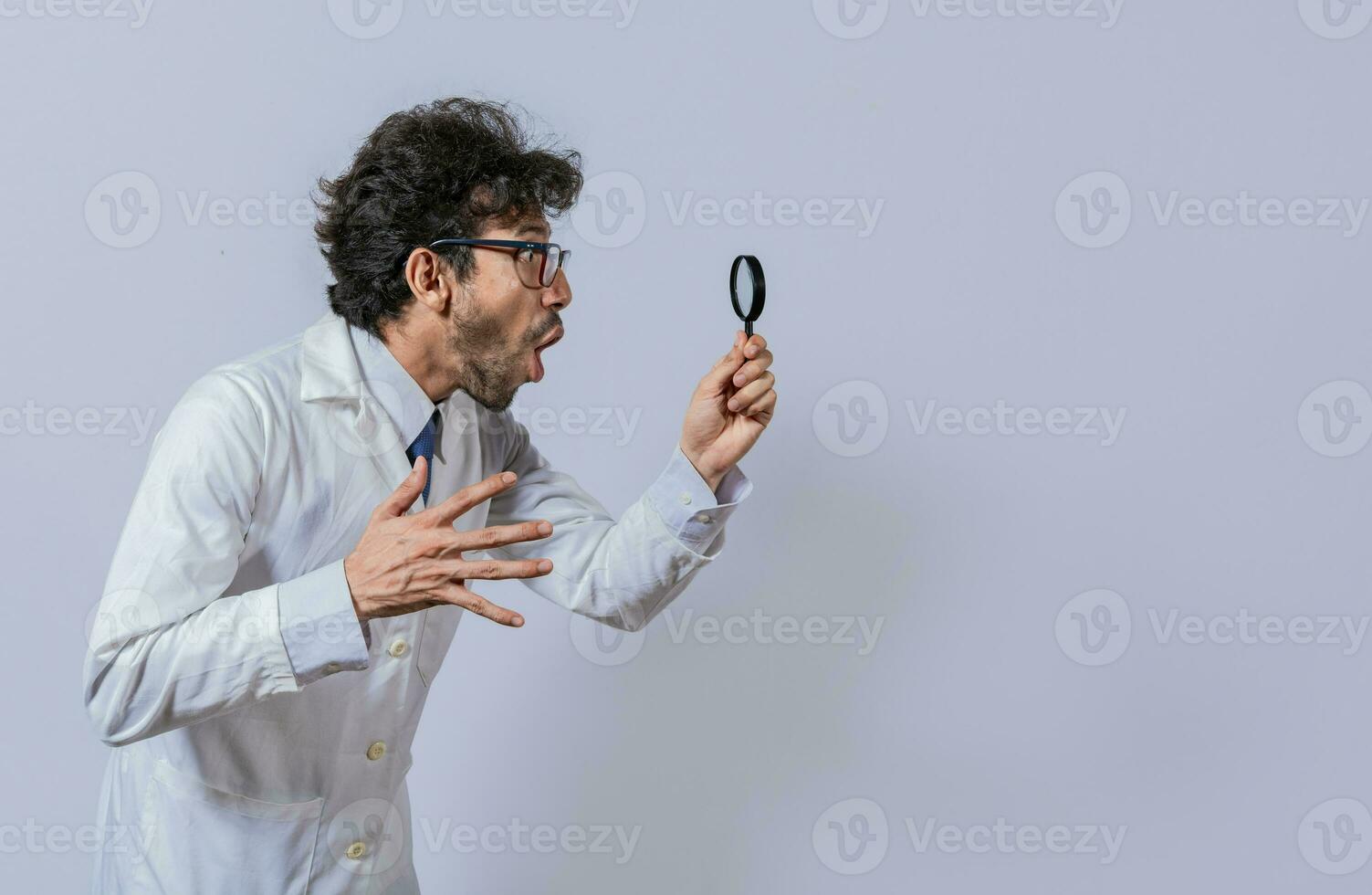 Scientist holding a magnifying glass looking to the side, Man in a white coat with a magnifying glass looking advertisement, Surprised scientist observing with a magnifying glass to the side photo