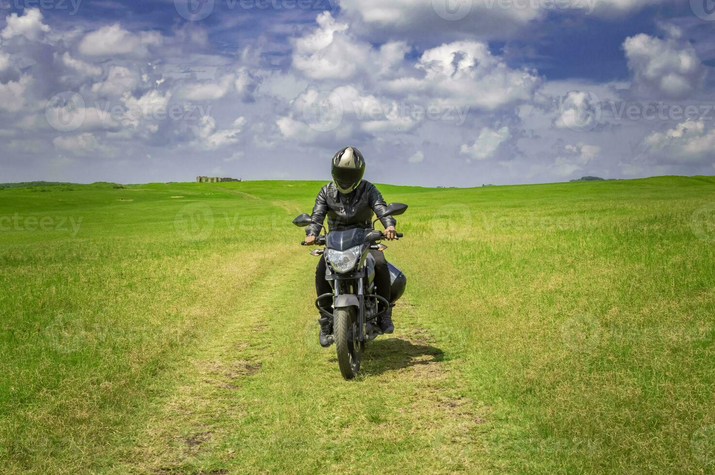 motorista hombre en un país camino, joven hombre en su motocicleta de viaje mediante el campo con Copiar espacio, hombre montando motocicleta en el campo foto
