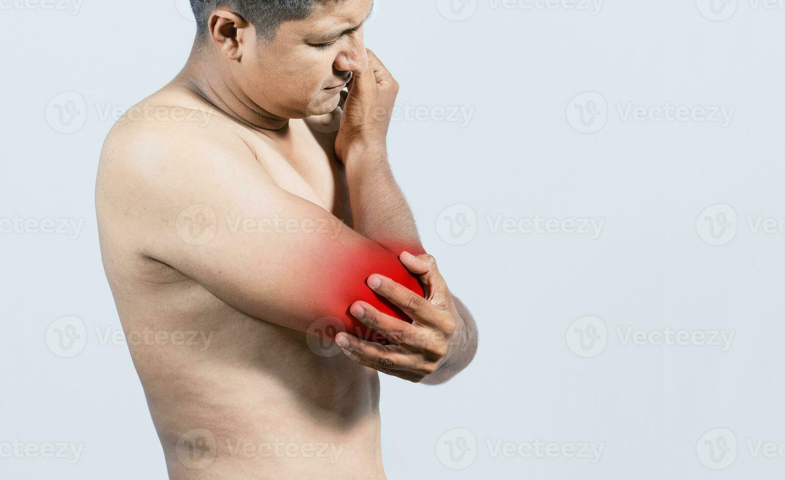 Person with elbow pain, concept of a people with elbow pain from rheumatism, shirtless man massaging sore elbow, man with elbow cramp photo