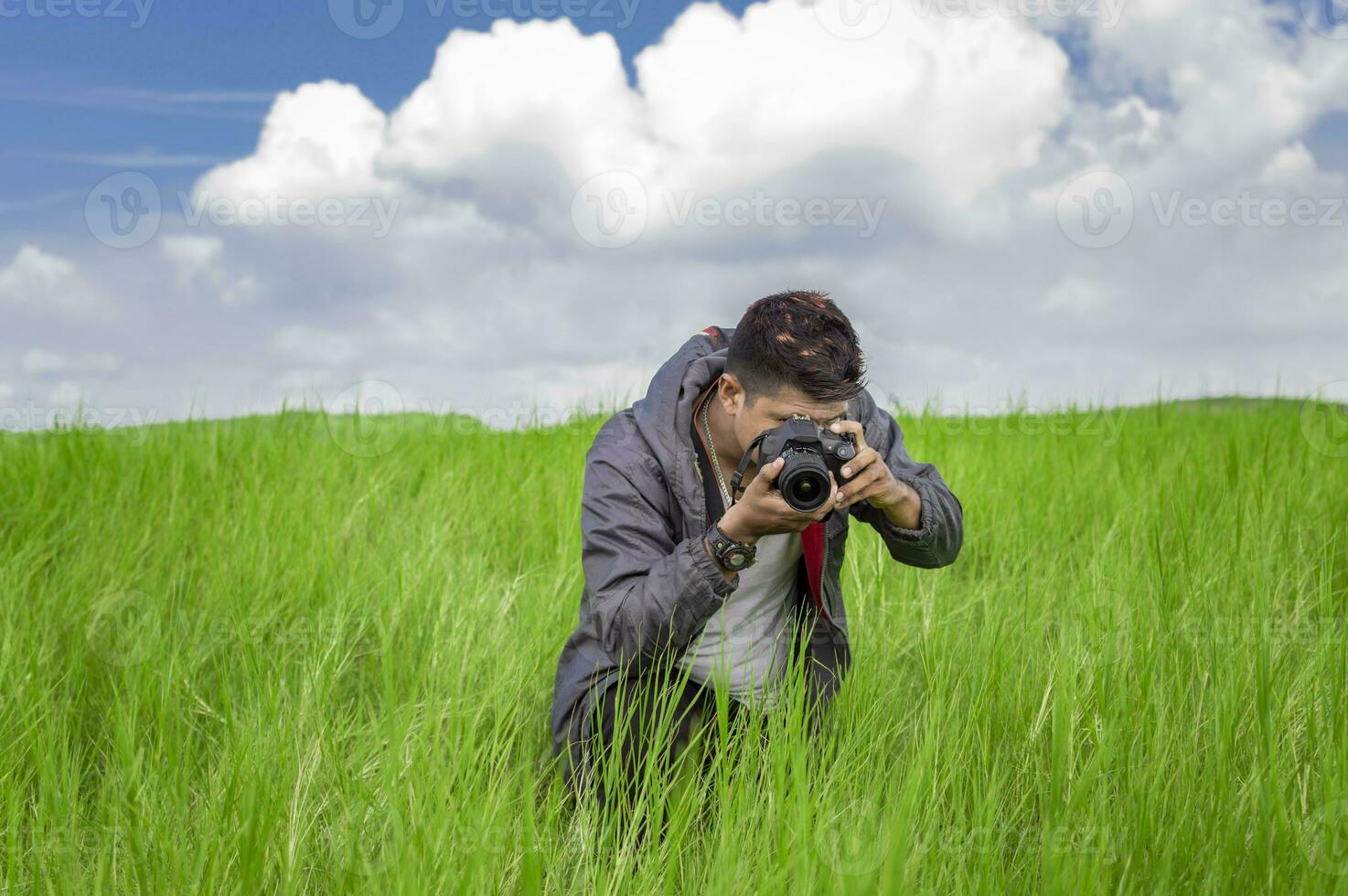 Man taking picture with camera in the field, photographer in the field taking a picture, Latino man in a green field taking a picture photo