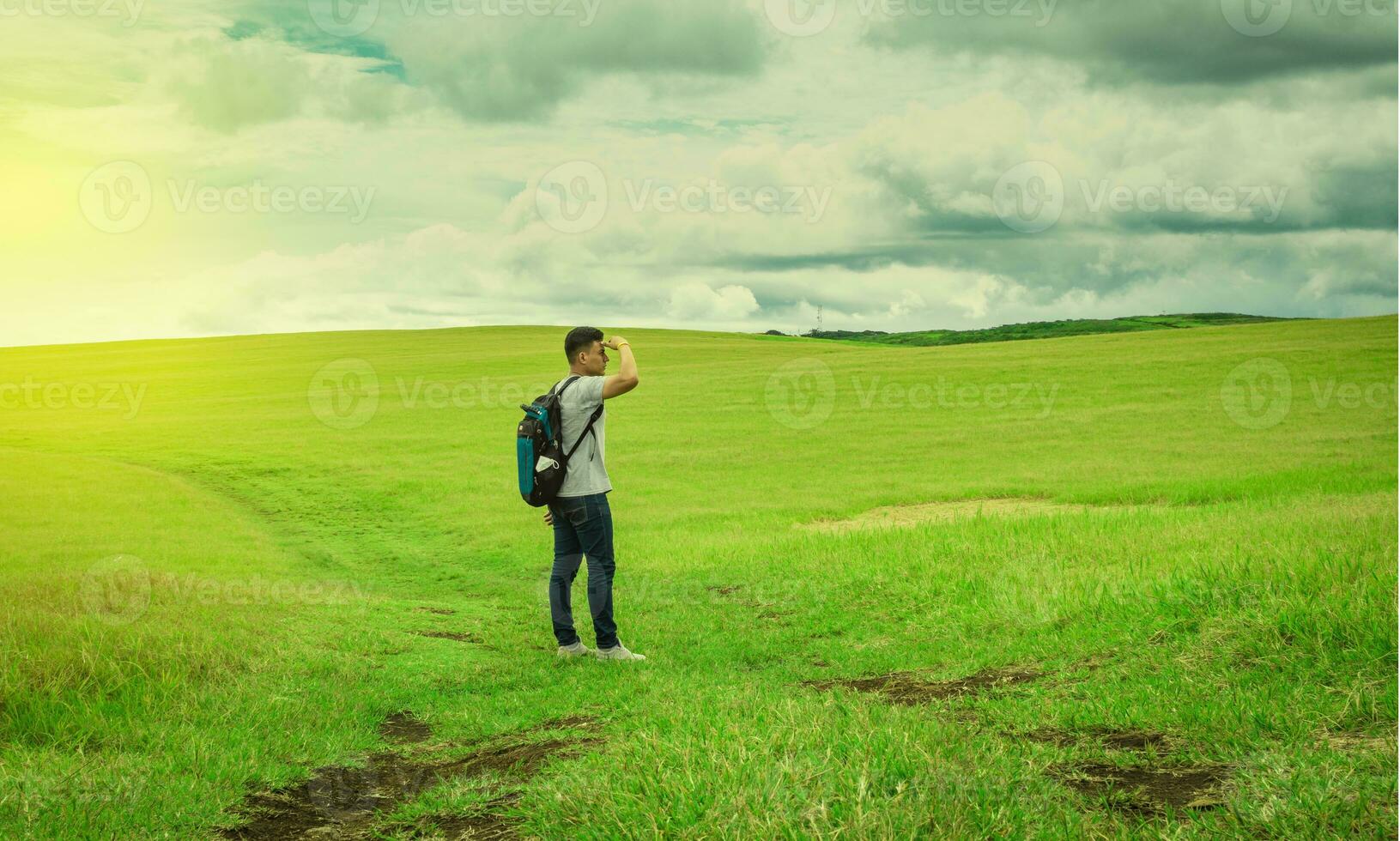 Adventurous man in the field, man with backpack in the field looking photo