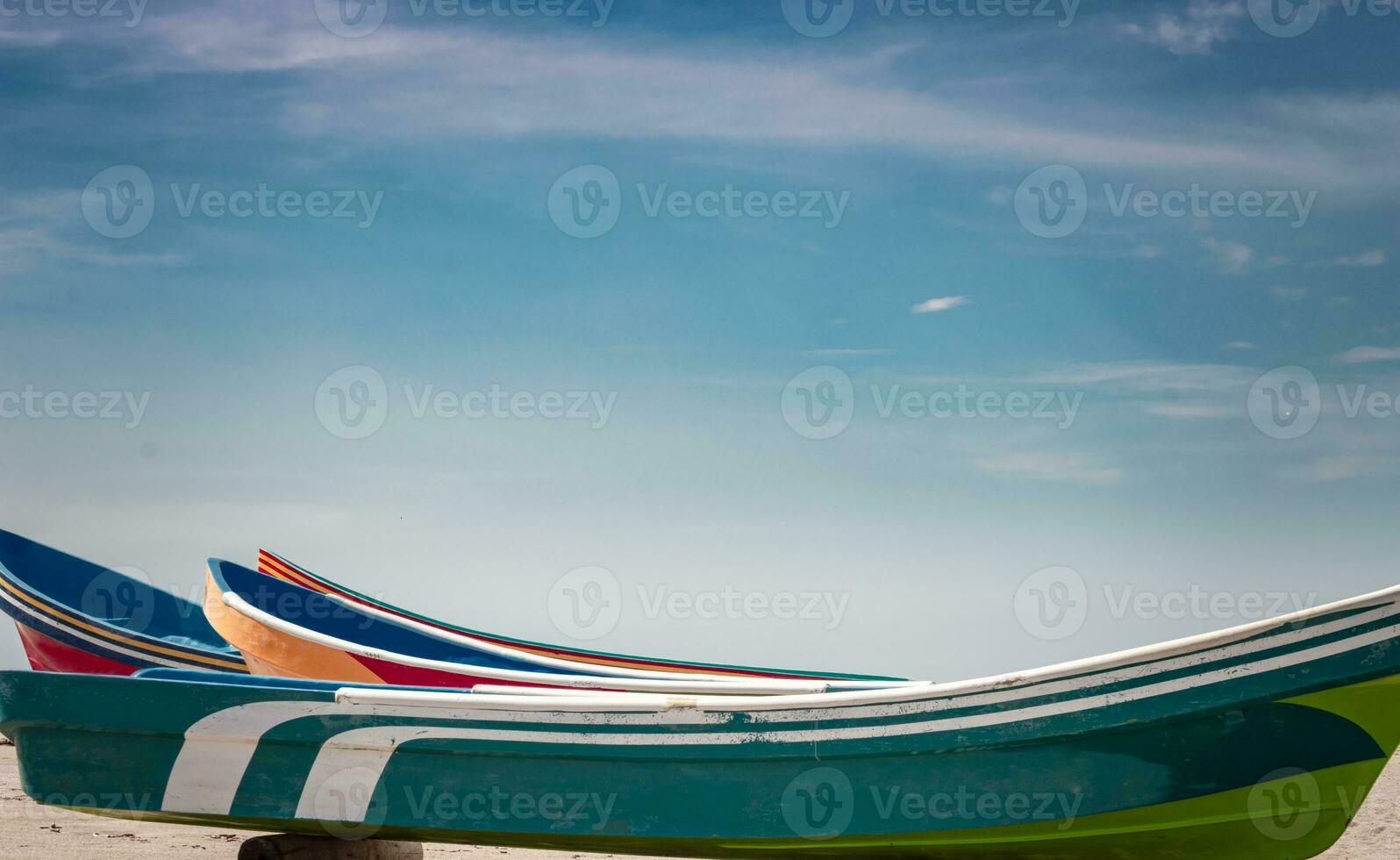 wooden boats parked on the sand, colorful fishing boats parked near the ocean, closeup of boats stranded on the ocean shore with blue sky and copy space photo