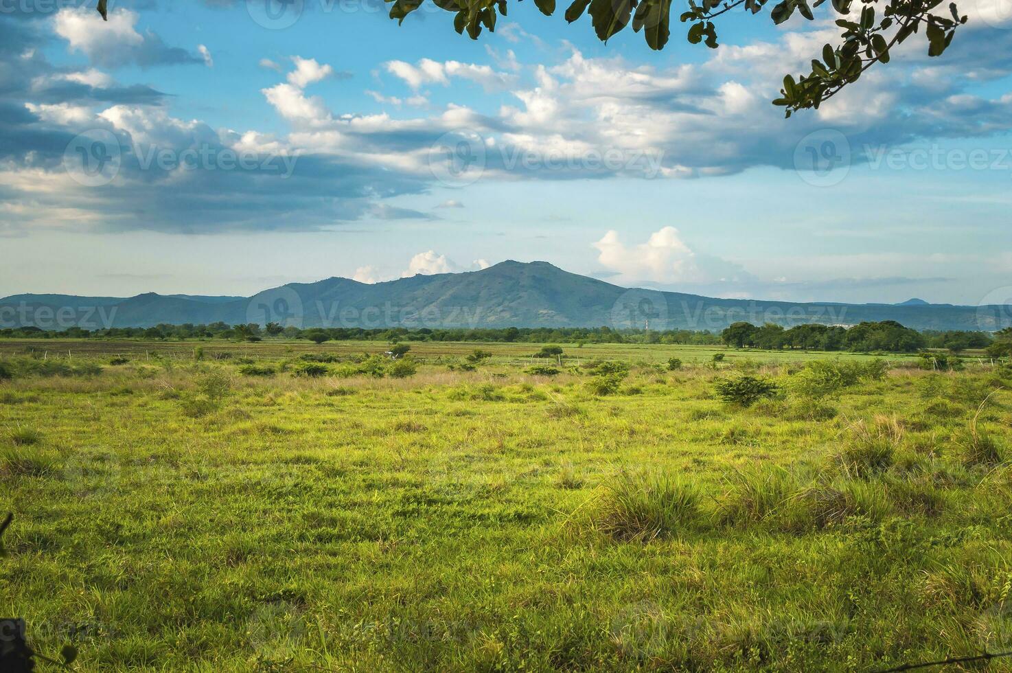 un montaña rodeado por vegetación, foto de un montaña con nubes y azul cielo en el campo