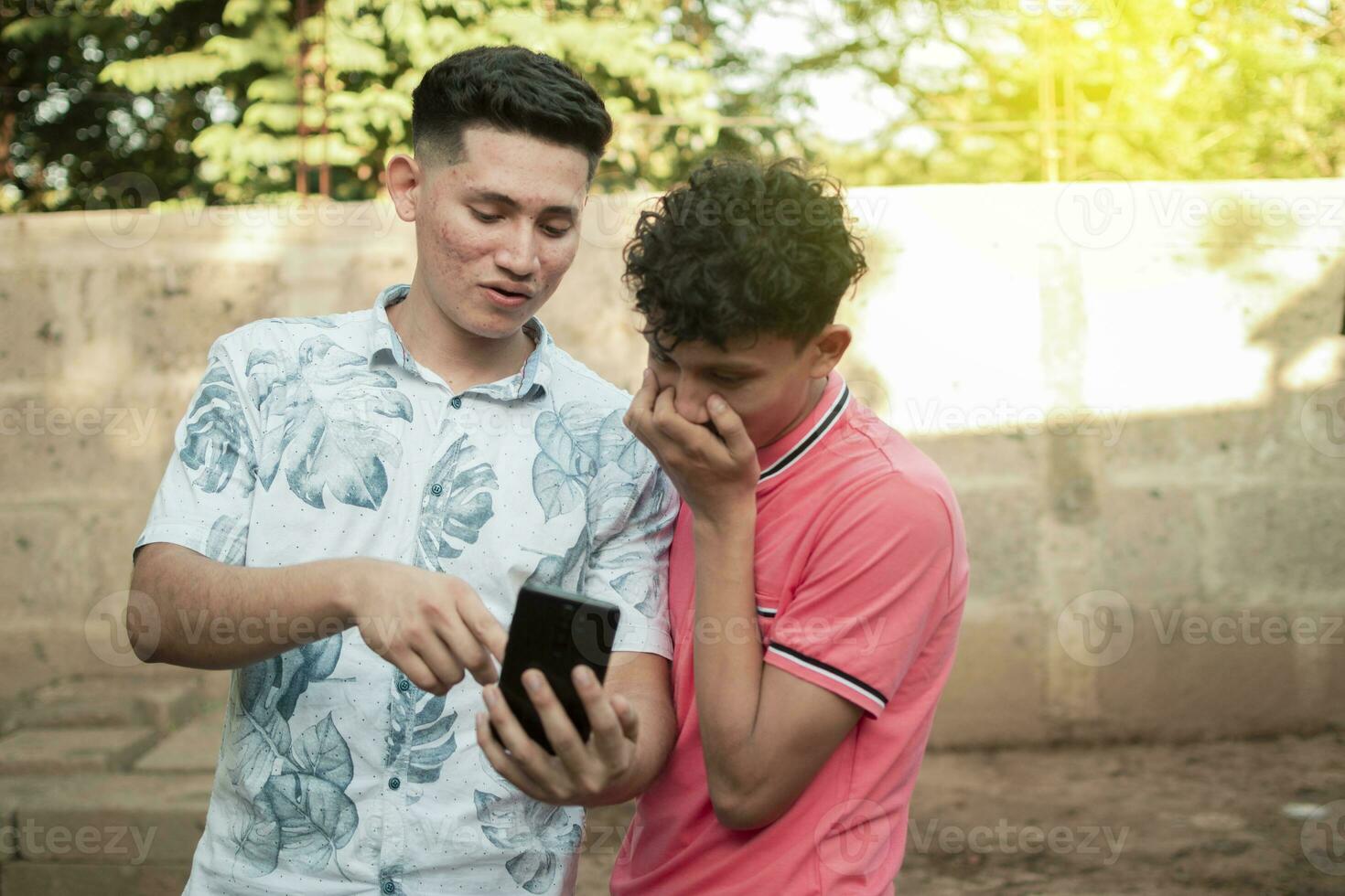 un joven hombre explicando con su célula teléfono a un joven hombre, un joven hombre demostración su célula teléfono a otro joven hombre foto