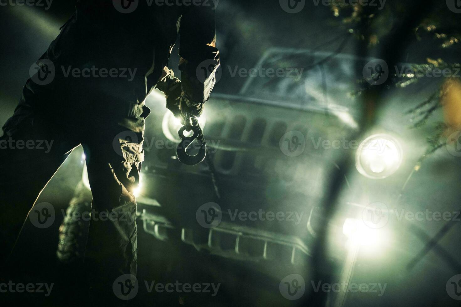 A Man with Winch Rope in His Hand Preparing For Recovery at Night photo