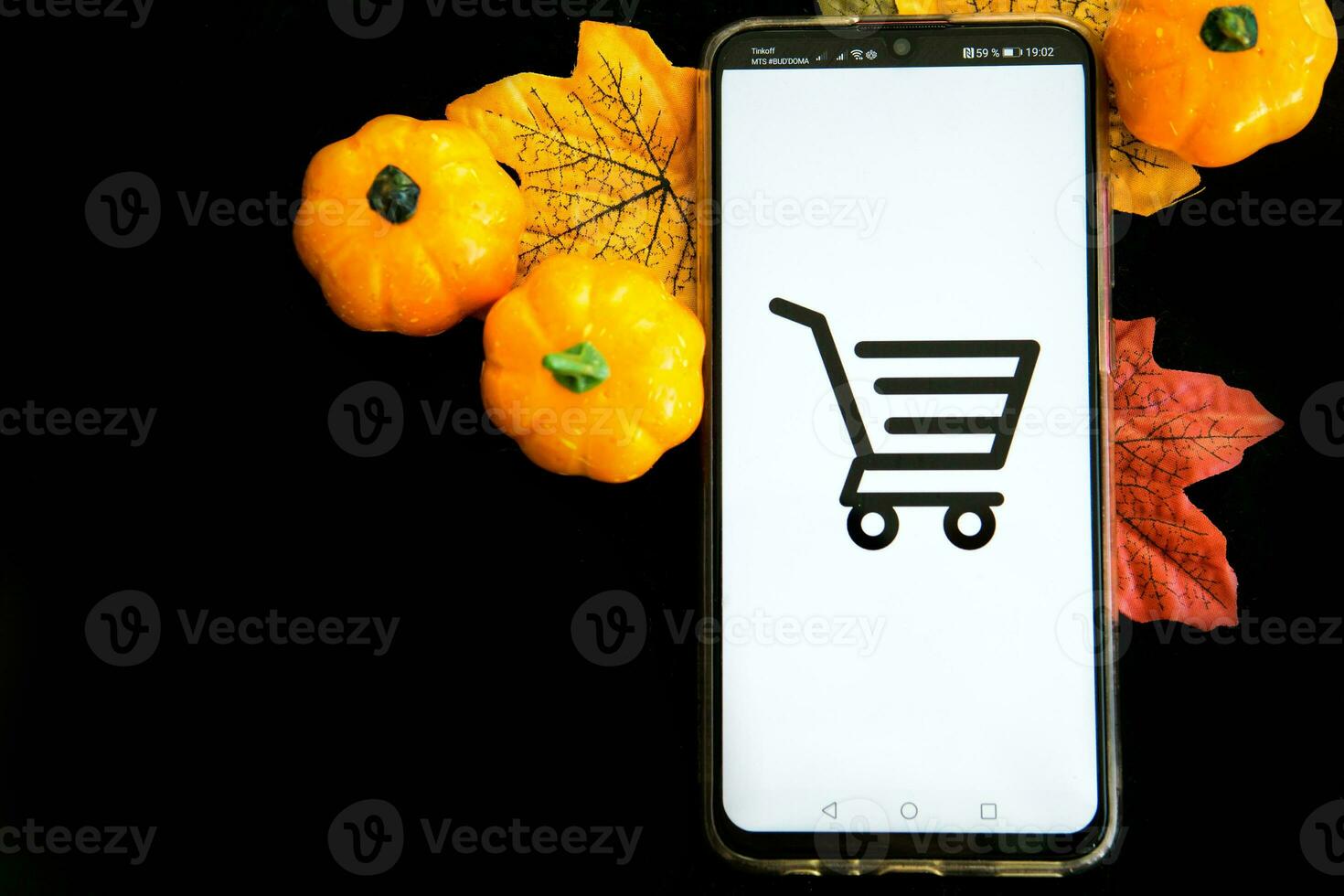 Tver, Russia, September 29, 2020, Smartphone and shopping cart on a black background. The concept of working in an online store. Sale, discounts and cyber Monday. photo