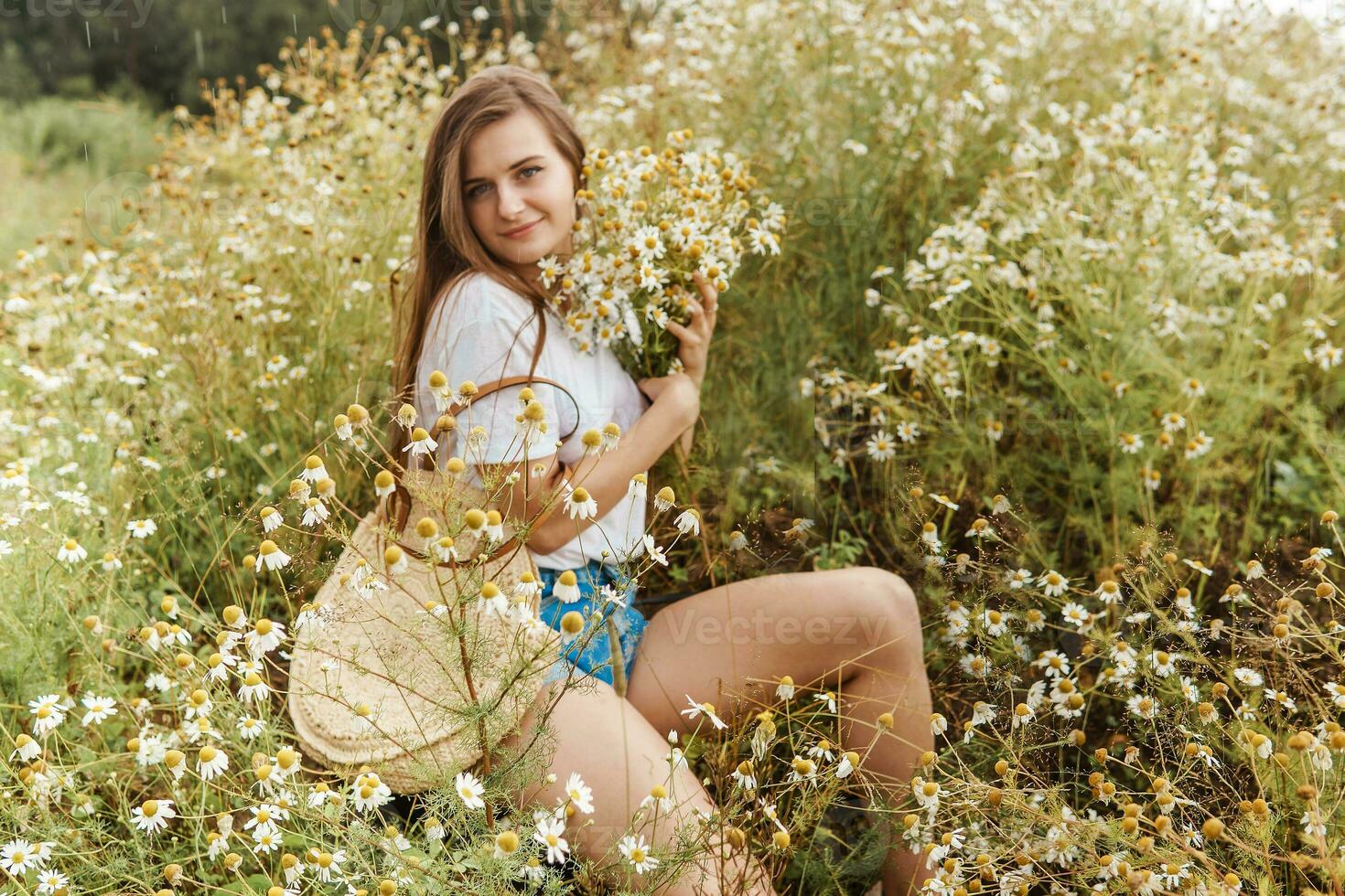 Beautiful young woman in nature with a bouquet of daisies. Field daisies, field of flowers. photo