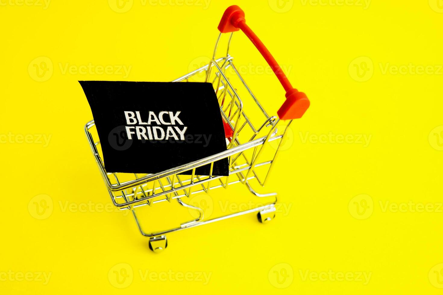 Shopping cart, and a black square that says black Friday on a yellow background. The topic of sales. photo