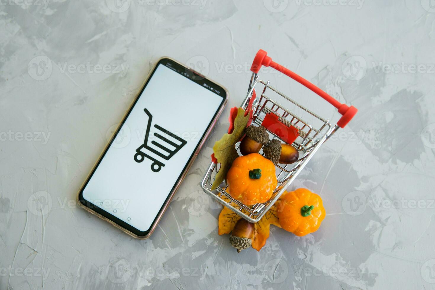 Tver, Russia, September 29, 2020, Smartphone and shopping cart on concrete background. The concept of working in an online store. Sale, discounts and cyber Monday. photo