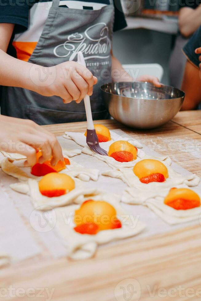 preparando un postre a un Cocinando Maestro clase. cestas con duraznos y fresas, hogar cocinando. de cerca, selectivo enfocar. pasteles, pasteles con duraznos desde soplo Pastelería. foto