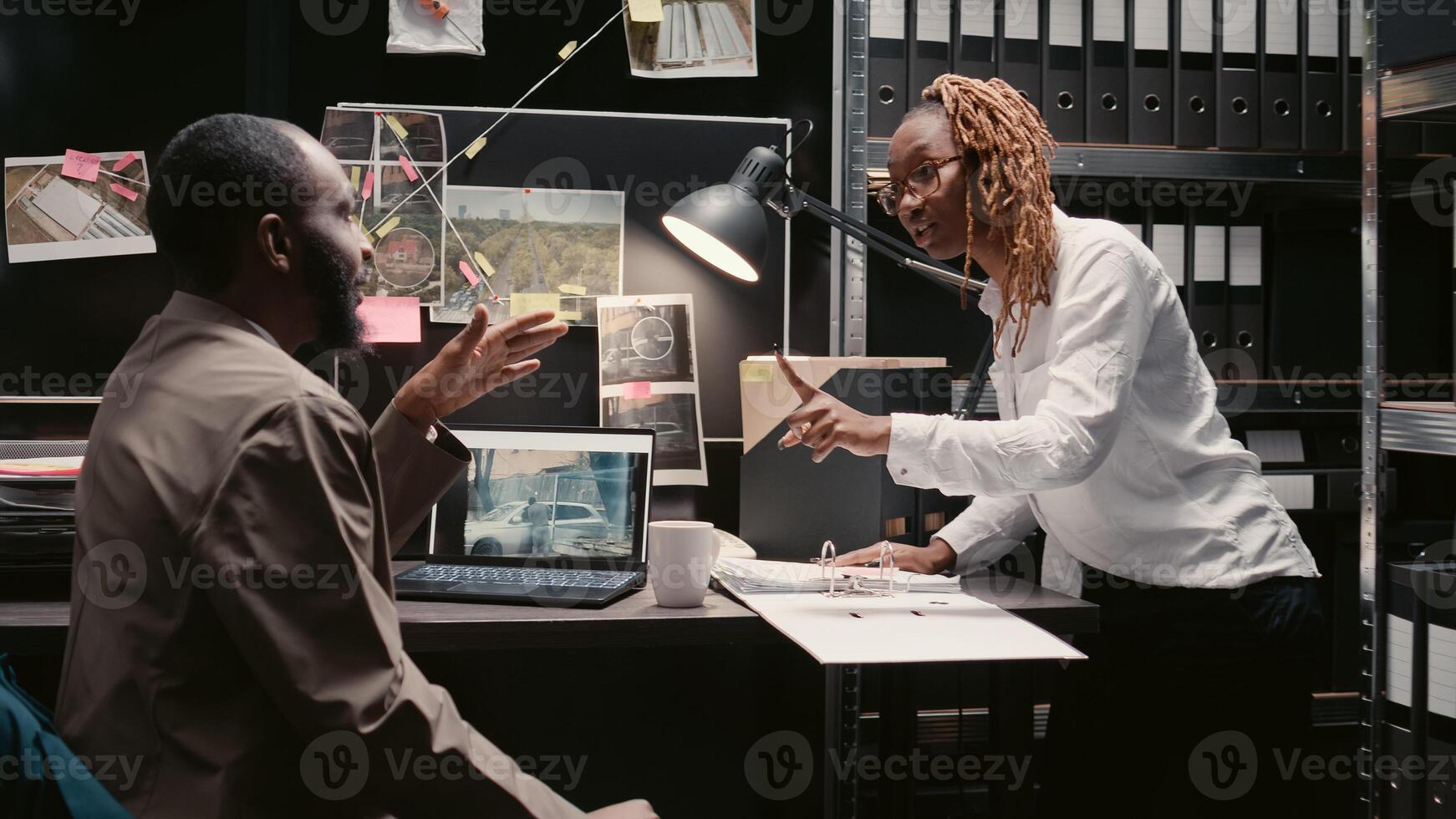 African american agents analyzing case reports in office, working on criminal investigation. Team of inspectors reading witness statements in police archive, looking at detective map. photo