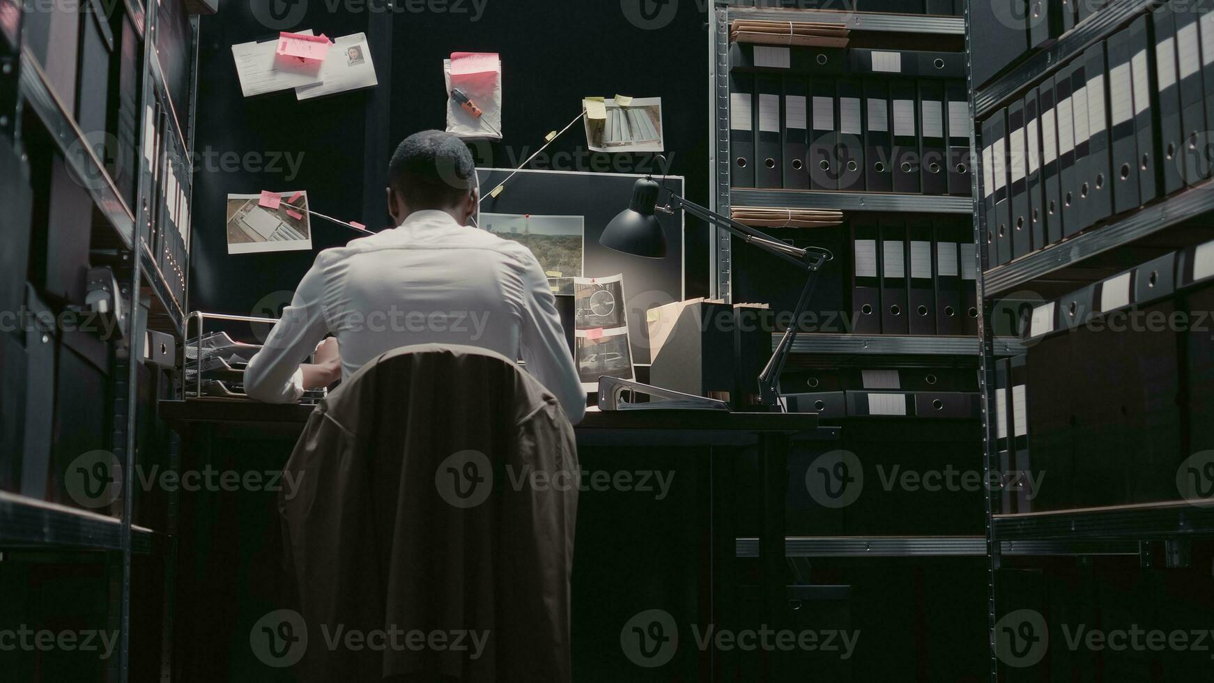 Police inspector analyzing forensic evidence on map, looking at professional detective board to solve crime. Male officer using background checks and records in incident room. Handheld shot. photo