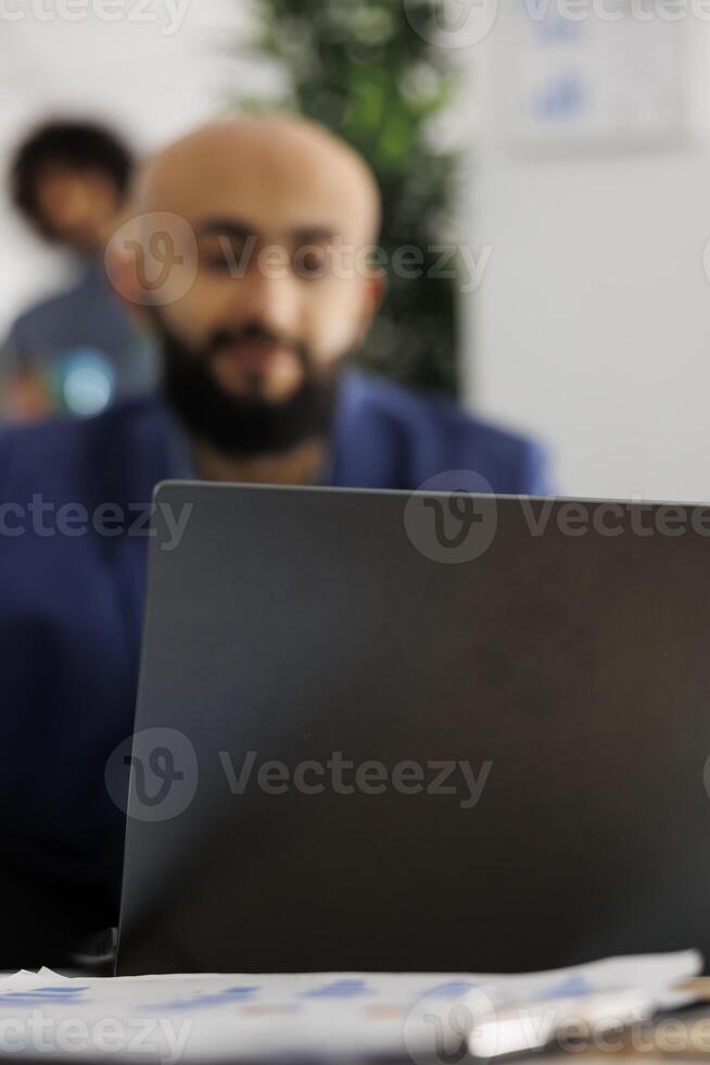 Arab company entrepreneur attending video call investor using laptop in busiess office. Executive manager discuss project strategy coworkers virtual meeting in coworking space photo