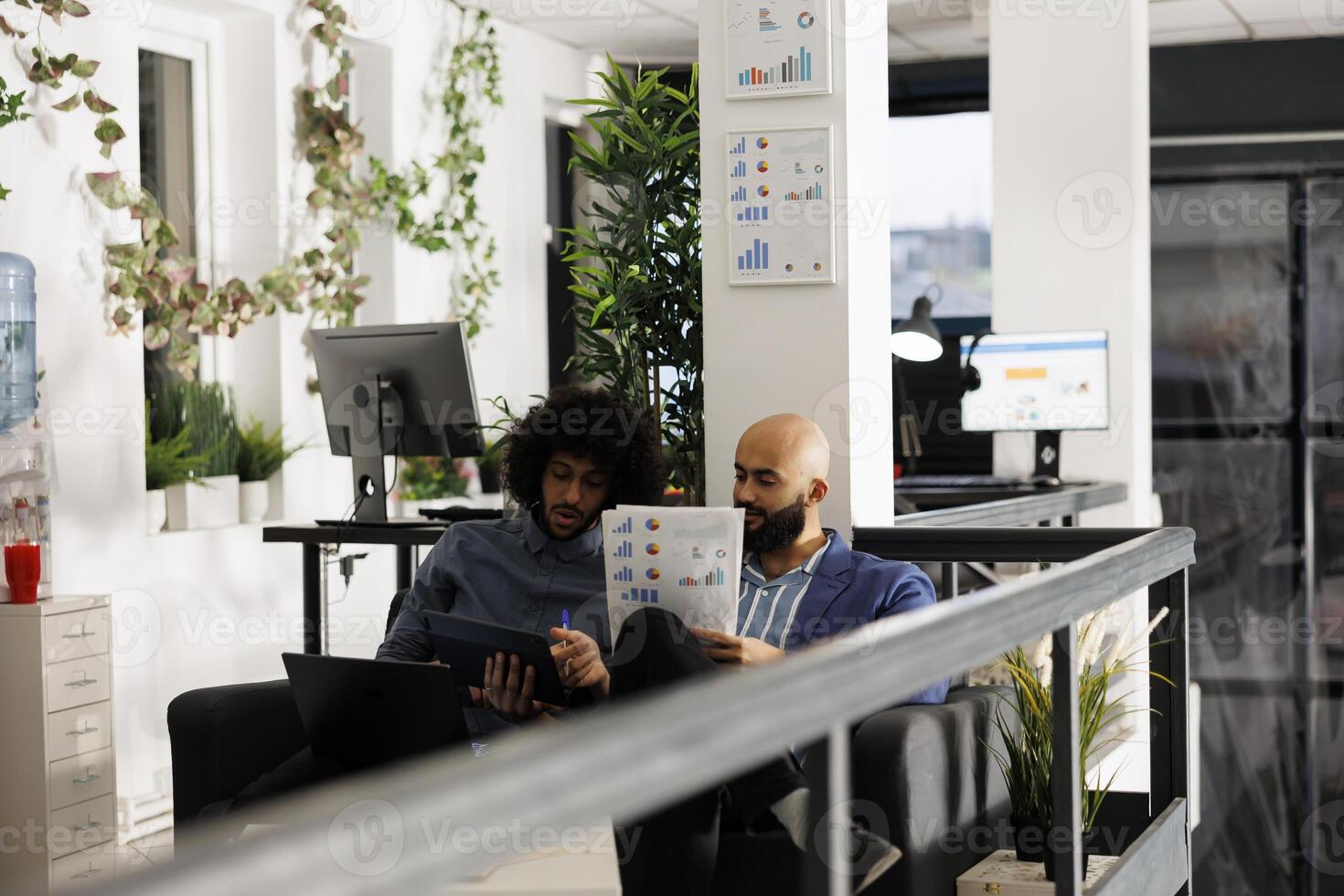 Arab entrepreneurs reviewing business strategies and analyzing papers with statistics charts. Company employees checking analytics report in corporate coworking space office photo