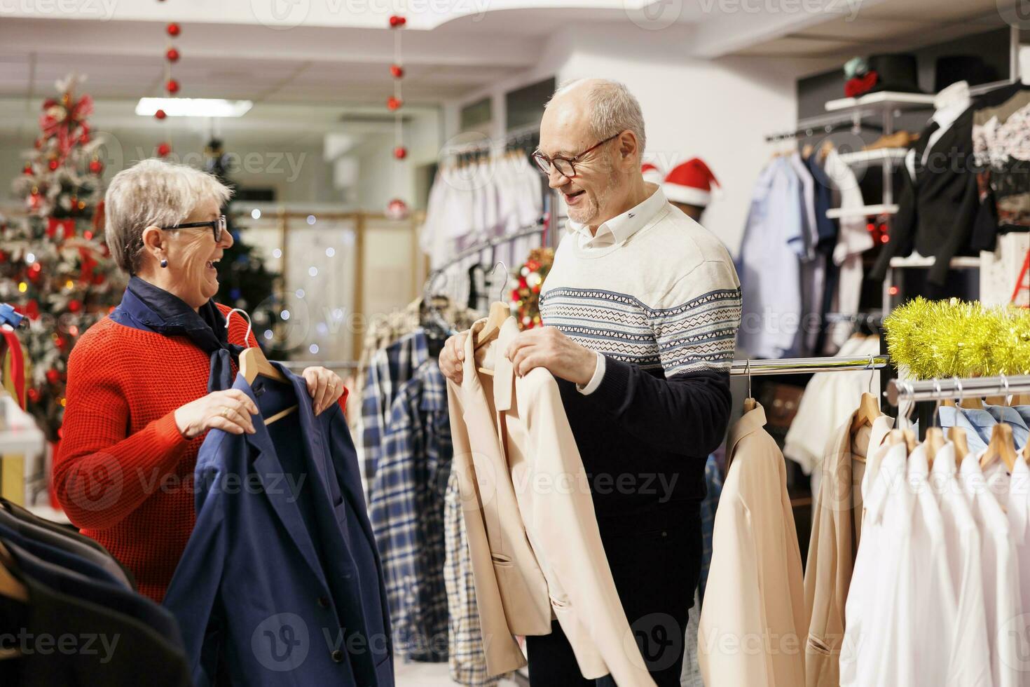 Senior people searching for jackets in retail store with festive ornaments,  buying clothes as presents for family on christmas eve. Cheerful couple  browsing through merchandise on sale. 33861738 Stock Photo at Vecteezy