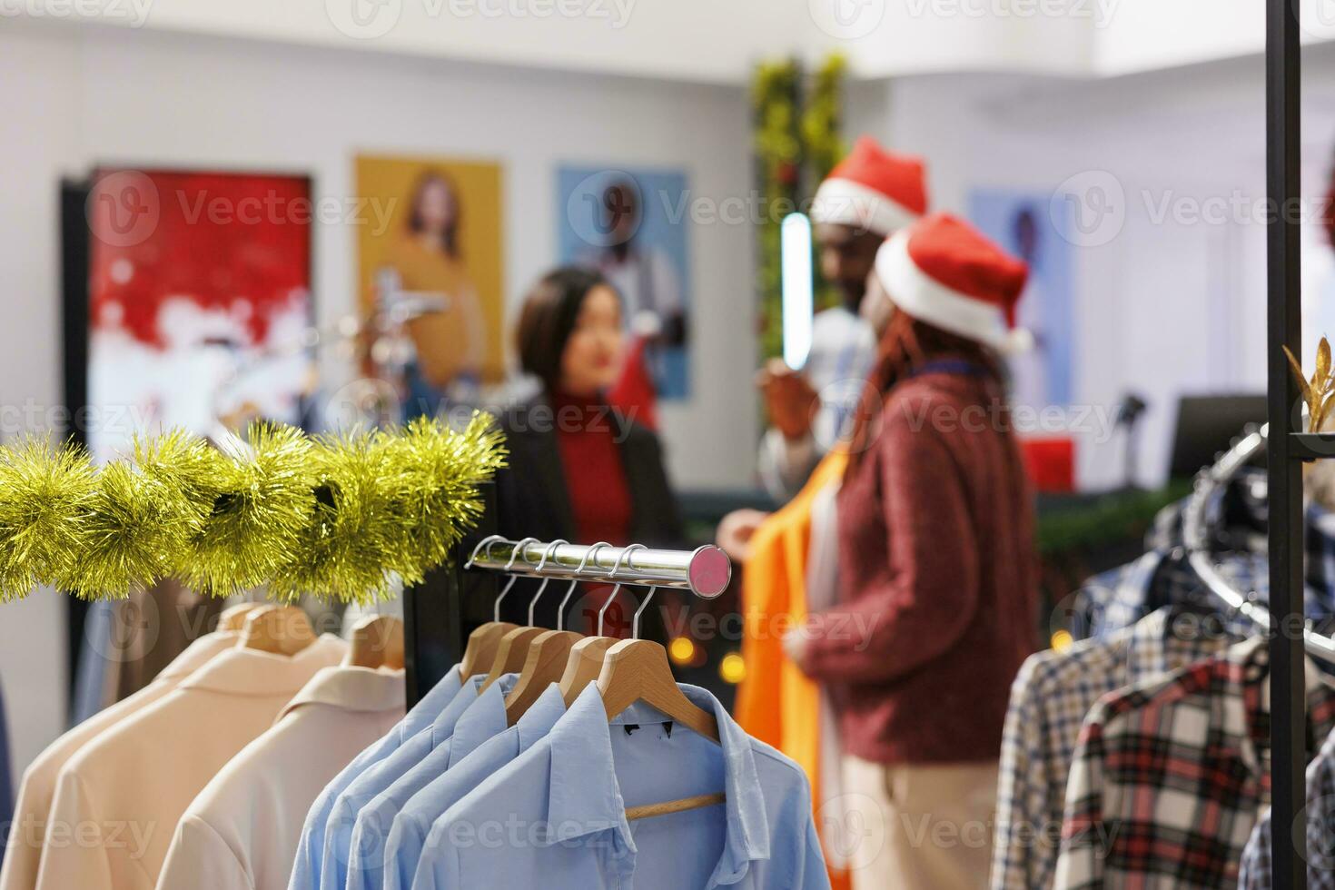 Selective focus of people checking items on hangers, woman asking staff members about available sizes at shopping center. Client searching for festive christmas outfit during holiday seasonal sales. photo