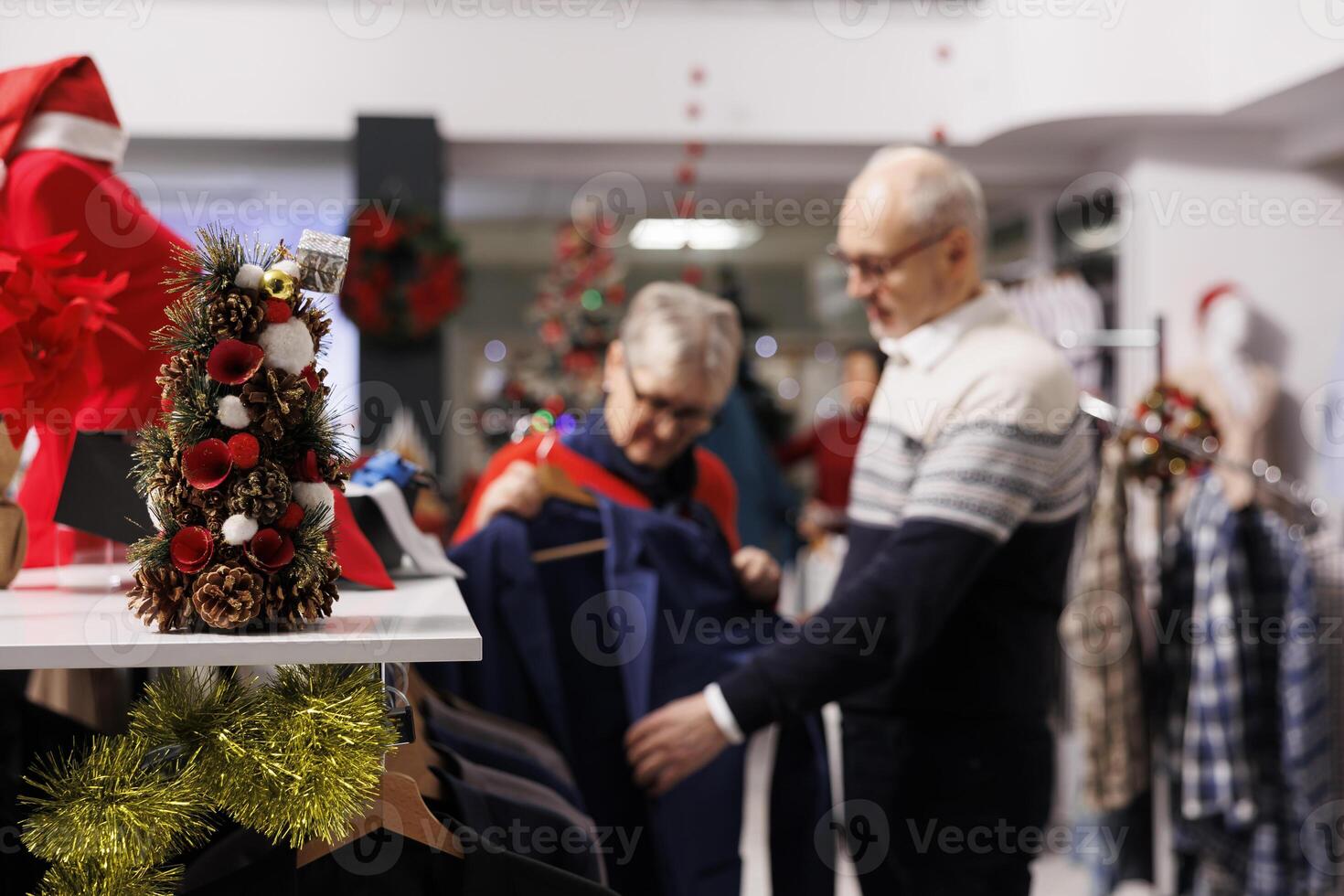 Selective focus of customers reviewing suit jacket on racks, looking for festive clothing to wear at christmas eve dinner. Persons checking blazers fabric in retail store, formal attire outlet. photo