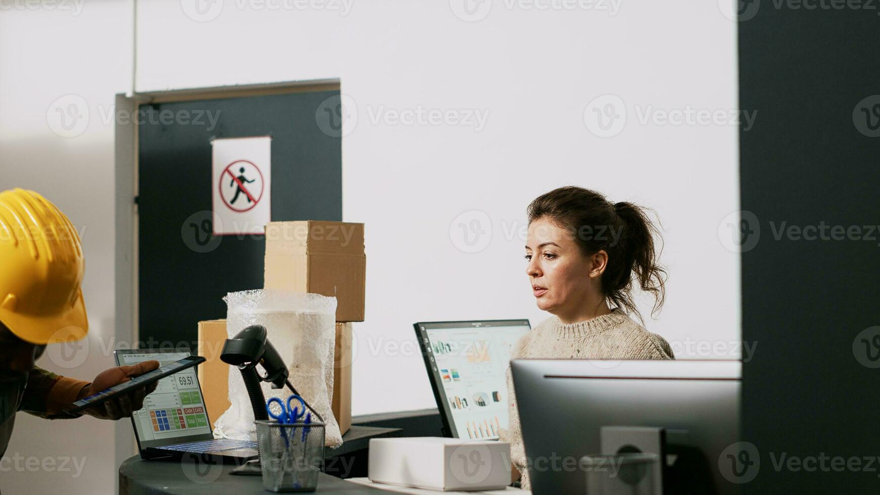 Young team inspecting orders on computer to work on shipment, preparing boxes for delivery in storage room. African american man and female manager discussing about merchandise. photo