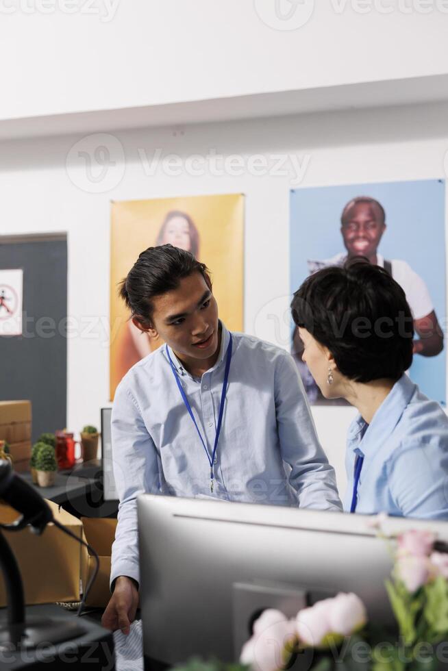 diverso compañeros de trabajo que se discute entrega informe, en pie a mostrador escritorio en ropa almacenar. empleados trabajando con de moda ropa, preparando paquetes para Envío en moderno boutique foto