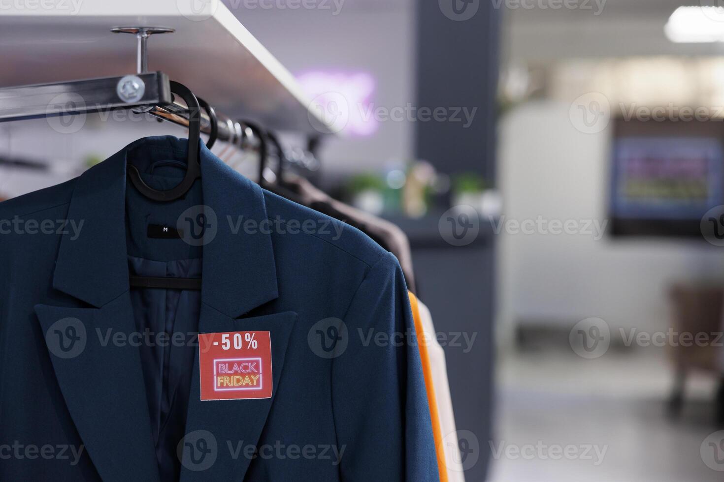 Close up of classic formal jacket with red Black Friday price tag hanging on cloth rack in empty modern fashion store. Special offers in clothing store during seasonal discount sales photo