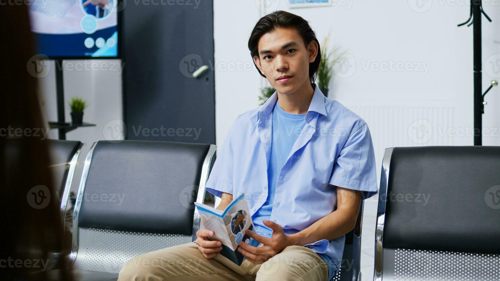 Portrait of nervous patient waiting to attend checkup visit with doctor, sitting in hospital lobby. Asian man with disease preparing for examination during checkup visit consultation. Medicine concept photo